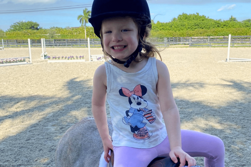A happy little girl enjoying her horse riding lesson