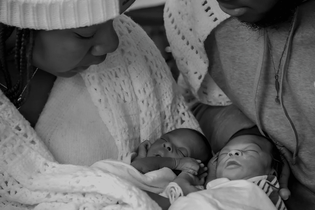 Newborn twins, Miracle and Faith, are held in their parents arms