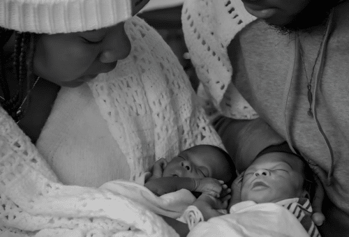 Newborn twins, Miracle and Faith, are held in their parents arms