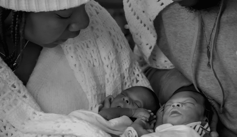 Newborn twins, Miracle and Faith, are held in their parents arms