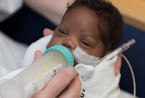 Explaining The Nonprofit Difference: Image of tiny African American baby being fed donor milk in the hospital