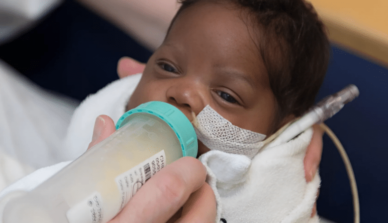 Explaining The Nonprofit Difference: Image of tiny African American baby being fed donor milk in the hospital