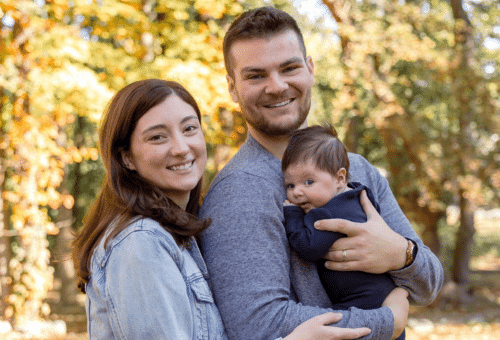 A mother and father smile while holding their newborn son