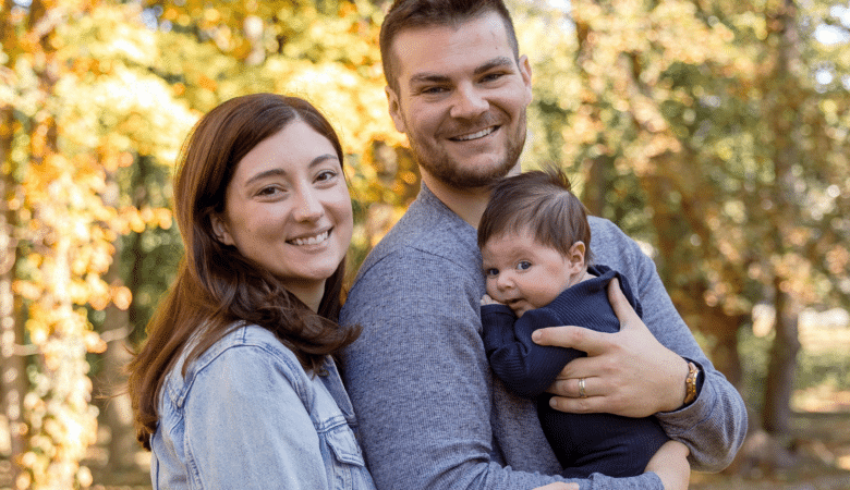 A mother and father smile while holding their newborn son