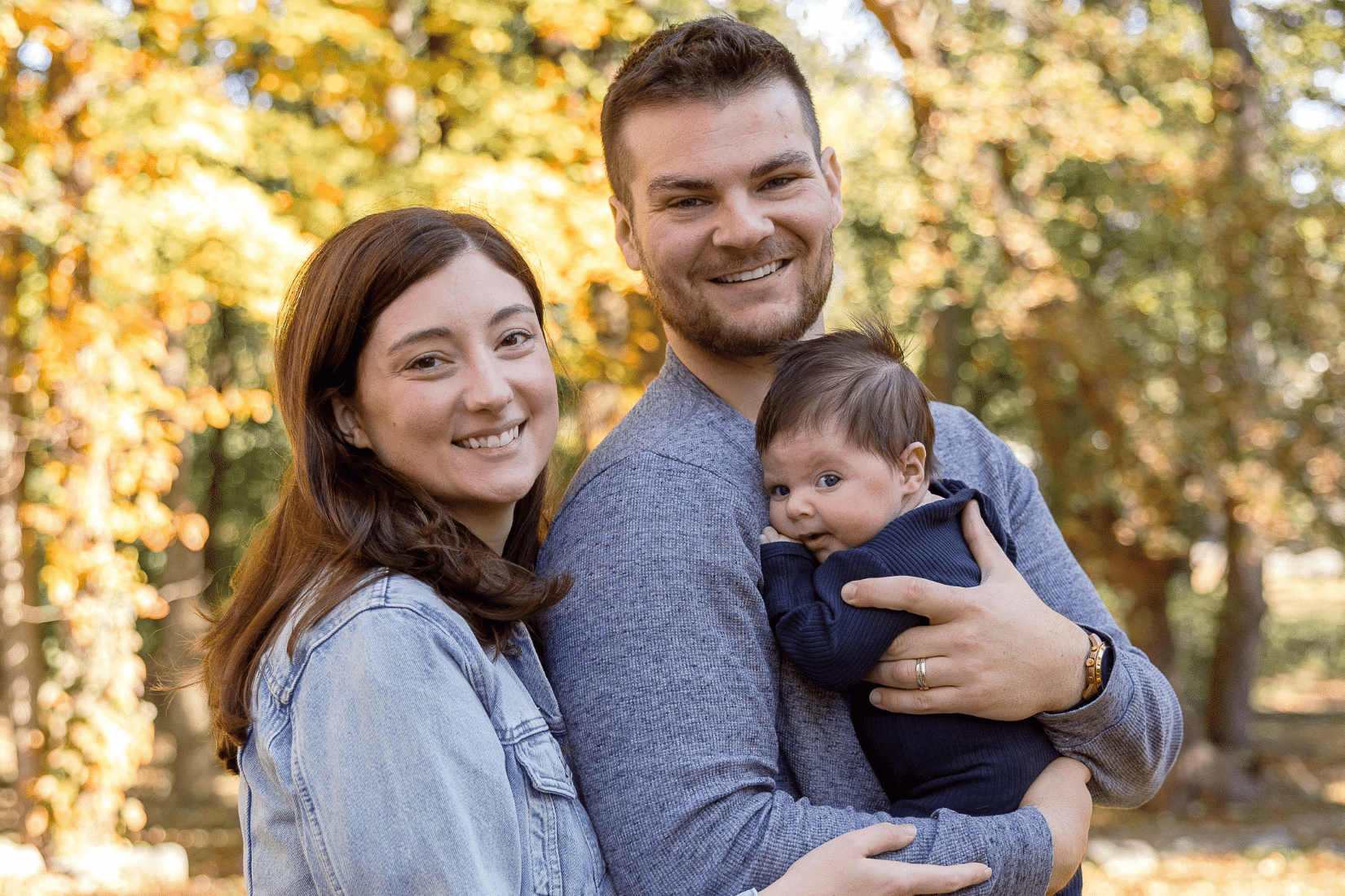 A mother and father smile while holding their newborn son